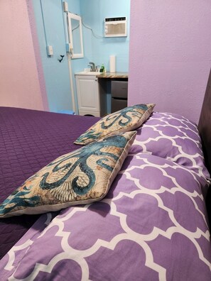 A bed with purple bedding and two decorative pillows. - Heart of Wailuku • Queen Bed + Kitchenette (Wailuku)