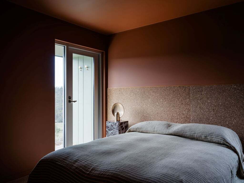 Une chambre à coucher avec un lit, une table de chevet et une porte donnant sur un balcon.