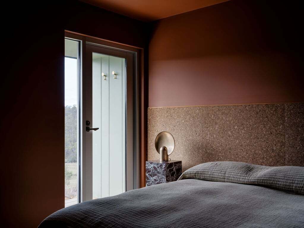 A bedroom with a bed, a nightstand, and a door leading to a balcony.