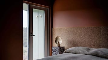 A bedroom with a bed, a nightstand, and a door leading to a balcony.