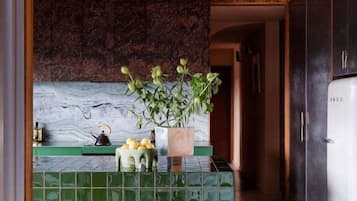 A kitchen with a green tiled backsplash, wooden ceiling, and a refrigerator.