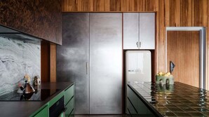 A kitchen with a marble countertop, green cabinets, and a stainless steel refrigerator. - Threefold - Freycinet Luxury Hosts (Swansea)