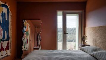 Quarto com cama grande, porta para o exterior e vista para o exterior.