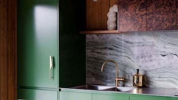 A kitchen with green cabinets, a marble backsplash, and a tiled countertop.