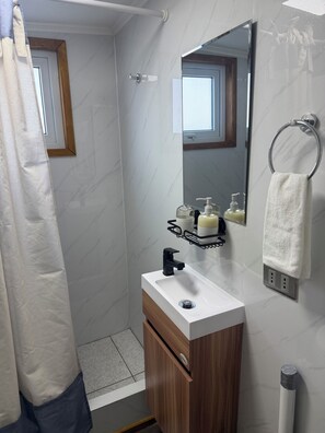 A bathroom with a shower, a sink with a mirror, and a towel rack.