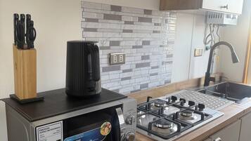 Uma cozinha compacta com fogão a gás, cafeteira e geladeira.
