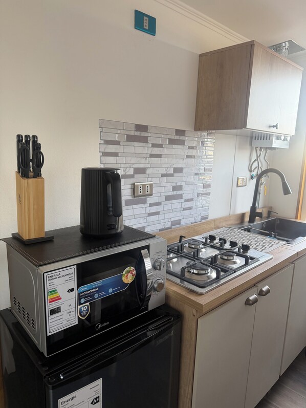 A compact kitchen with a gas stove, a coffee maker, and a refrigerator.