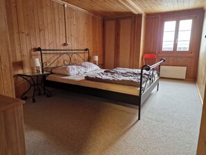 Ein Einzelbett mit Metallgestell in einem Raum mit Holzwänden und geneigter Decke.