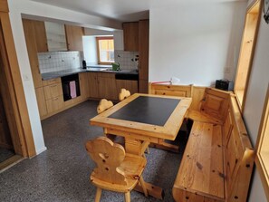 Eine kompakte Küche mit Holzausstattung, einer schwarzen Arbeitsplatte und einem Esstisch mit Bänken.