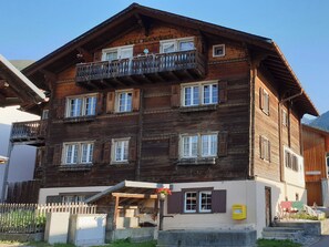 Ein mehrstöckiges Holzhaus mit Balkonen und Fenstern, ein kleiner Eingangsbereich mit einer Tür und einem sichtbaren Briefkasten.