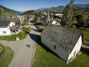 Ein ländliches Dorf mit traditionellen Häusern, einer Kirche und einer Bergkulisse.