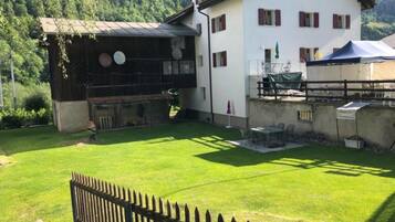 Ein zweistöckiges Haus mit umzäuntem Garten, einem Grillplatz und einem Tisch mit Sitzgelegenheit draußen.