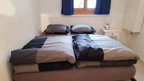 Ein Doppelbett mit Holzrahmen und einer Matratze auf Holzboden.