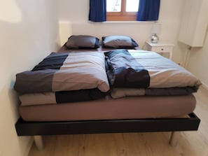 Ein Doppelbett mit Holzrahmen und einer Matratze auf Holzboden.