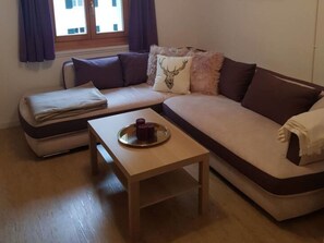 A living room with a sofa, a small table, and a window with curtains.
