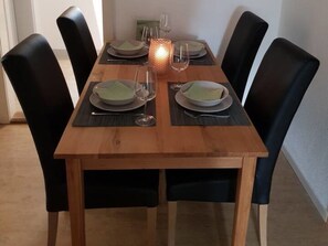 A rectangular dining table with a wooden finish, surrounded by black chairs.