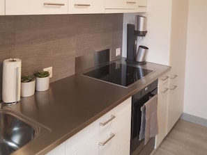 A modern kitchen with a stainless steel countertop, a built-in oven, and white cabinetry. - Casa Spescha, Tavanasa, (Tavanasa), 65059B by Interhome (Tavanasa)
