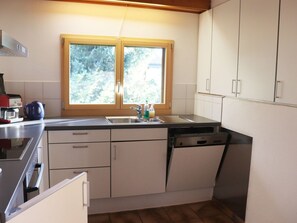 Eine Küche mit Fenster, Schränken, Spüle und Geschirrspüler.