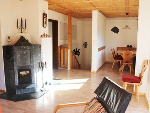 Sala de estar com lareira, móveis de madeira e um espaço para refeições.