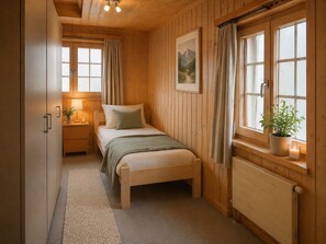 A cozy bedroom with a wooden bed, a nightstand with a lamp, a window with curtains, and a radiator.