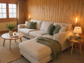 A cozy living room with a sofa, two side tables, a lamp, and a vase with a plant.