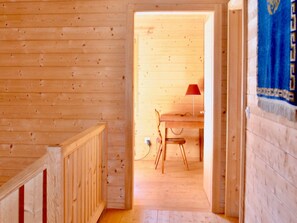 Un interior de madera con suelo de madera, una mesa con una silla y una lámpara roja.