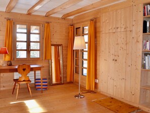Una habitación de madera con escritorio, silla, lámpara y estantería.