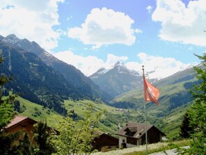 A mountain landscape with a flag, houses, and a clear sky.