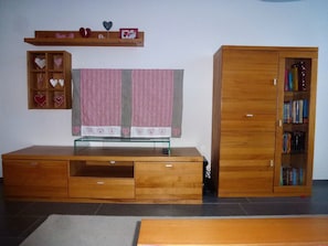 A wooden entertainment center with a flat-screen TV, a bookshelf, and a small shelf with decorative items. - Denter Uauls Jucker, Vella, (Vella), 44012B by Interhome (Vella)