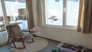 A room with a rocking chair, a table with a cup, and a window with curtains. - Denter Uauls Jucker, Vella, (Vella), 44012B by Interhome (Vella)