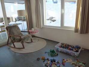 A room with a rocking chair, a table with a cup, and a window with curtains. - Denter Uauls Jucker, Vella, (Vella), 44012B by Interhome (Vella)