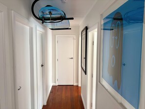 A hallway with wooden flooring, white doors, and a ceiling fan. - Lorenzen Bay Bungalow by The Sea (Raglan)
