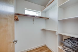 Um closet amplo com piso de madeira, paredes brancas e uma janela.