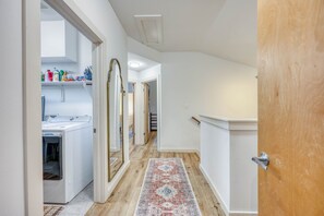 A hallway with a washing machine, a large mirror, and a wooden door. - *New* Austin Skyline Vista 🦚 | Rooftop Views, South First Vibes 🌵🎸 (Austin)