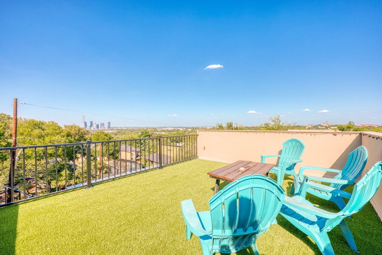 Een balkon met kunstgras, een tafel en blauwe stoelen.