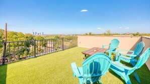 A balcony with artificial grass, a table, and blue chairs. - *New* Austin Skyline Vista 🦚 | Rooftop Views, South First Vibes 🌵🎸 (Austin)