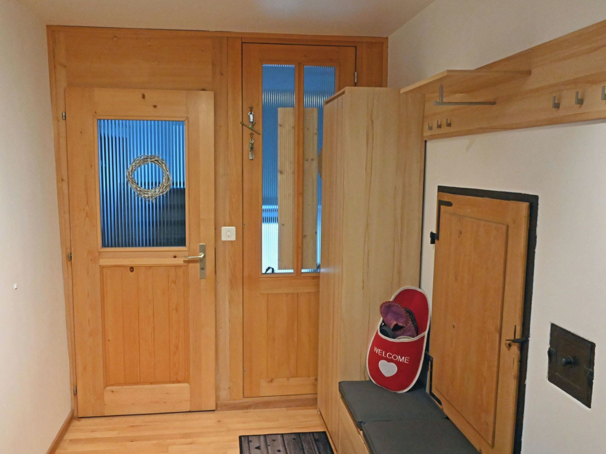 Une porte en bois avec une fenêtre, un paillasson et un banc.