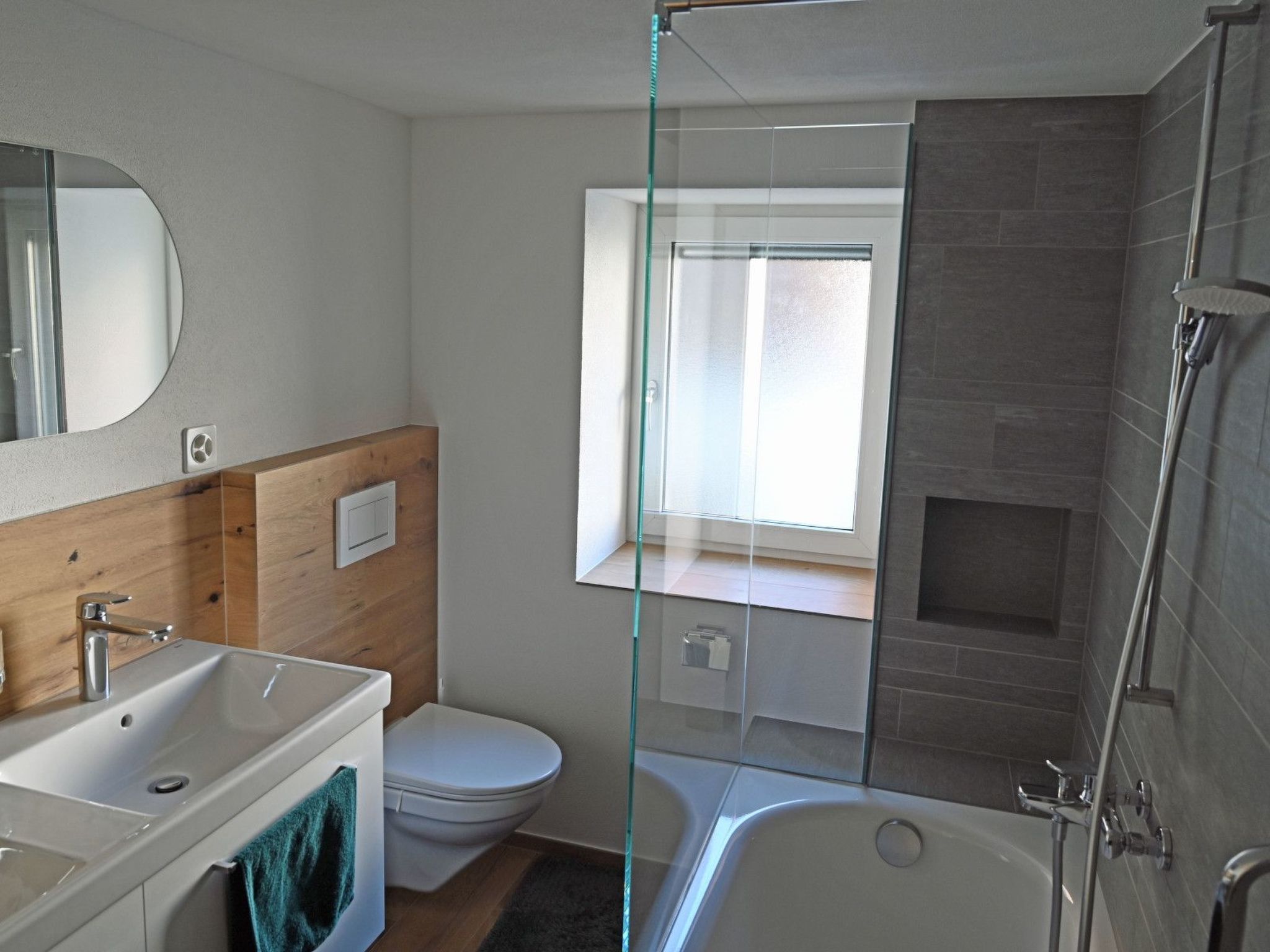 Ein modernes Badezimmer mit einer Duschkabine aus Glas, einer weißen Toilette und einer Badewanne.