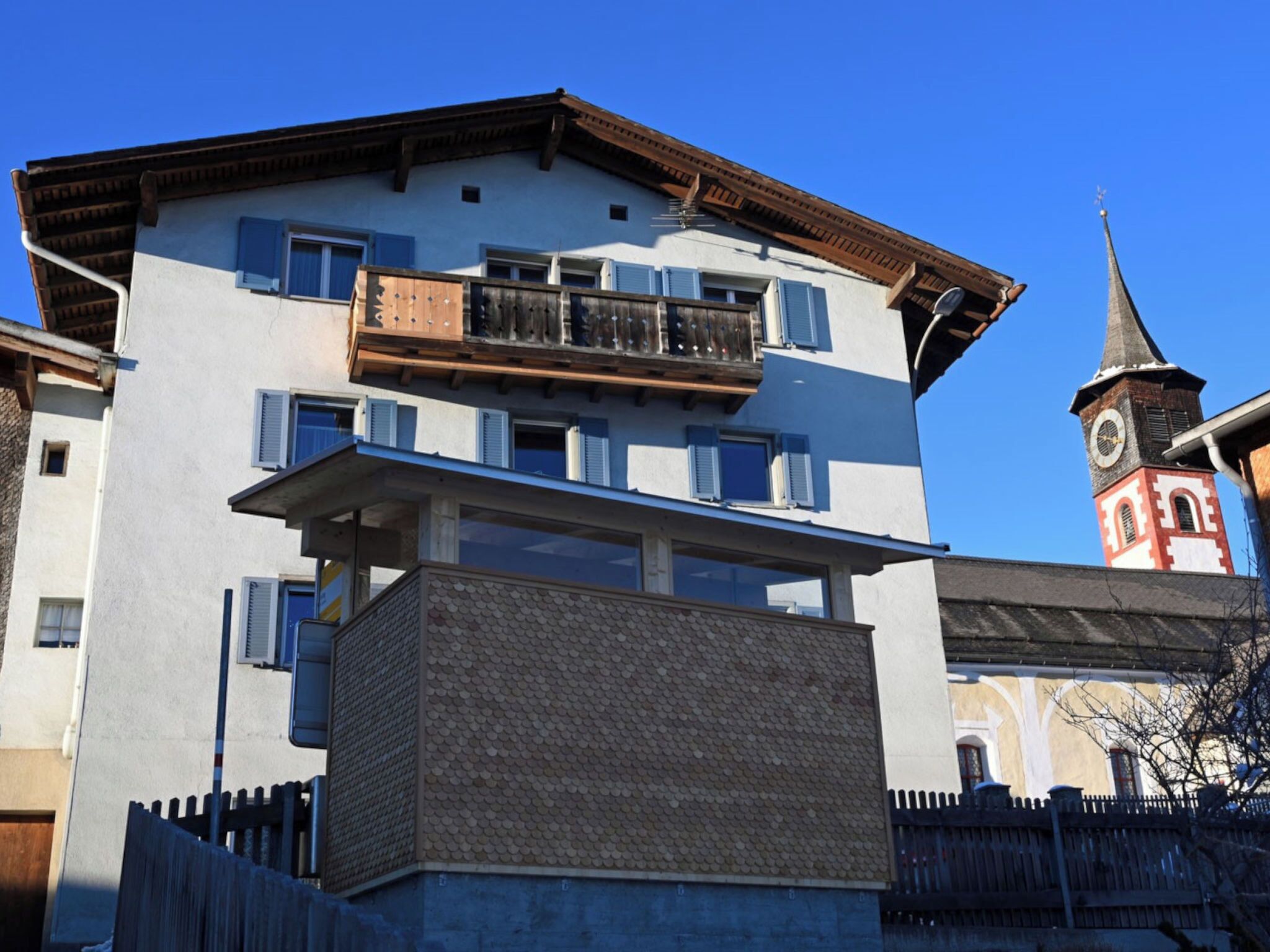 A multi-story building with balconies, a clock tower, and a clear sky.