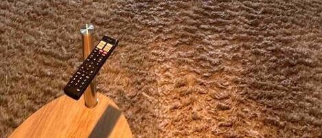 A living room with a sofa, a coffee table, and a remote control on it.