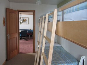A room with bunk beds, a door, a desk, and a chair.