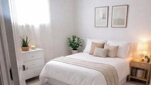 A bedroom with a bed, bedside tables, a nightstand, a potted plant, and a rug. - Your Home Away From Home in Courtice (Clarington)