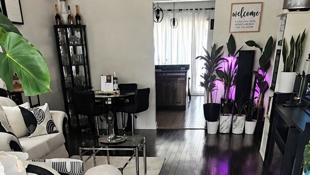 A modern living room with a sofa, a dining table, and a kitchen area. - Your Home Away From Home in Courtice (Clarington)