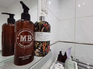 A bathroom with a hand and body lotion dispenser, a bottle of lotion, and a soap dispenser. - Spacious Clean Central Near Train Stn & University (Edinburgh)