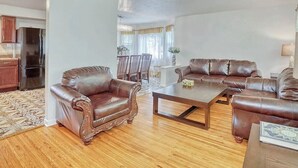 A living room with a brown leather sofa set, a coffee table, and a dining area with chairs and a table. - Spacious 5-bedroom house in charming Irondequoit with AC (Irondequoit)