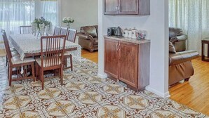 A dining area with a table set for four, surrounded by chairs, and a cabinet with kitchen items. - Spacious 5-bedroom house in charming Irondequoit with AC (Irondequoit)