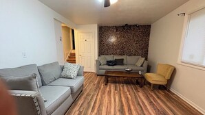 A living room with a grey sofa, a yellow armchair, and a patterned wall. - Spacious 5-bedroom house in charming Irondequoit with AC (Irondequoit)