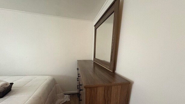 A bedroom with a bed, a wooden dresser, and a mirror. - Spacious 5-bedroom house in charming Irondequoit with AC (Irondequoit)
