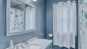 A bathroom with a double sink, a toilet, a shower curtain, and a mirror with lights. - Spacious 5-bedroom house in charming Irondequoit with AC (Irondequoit)