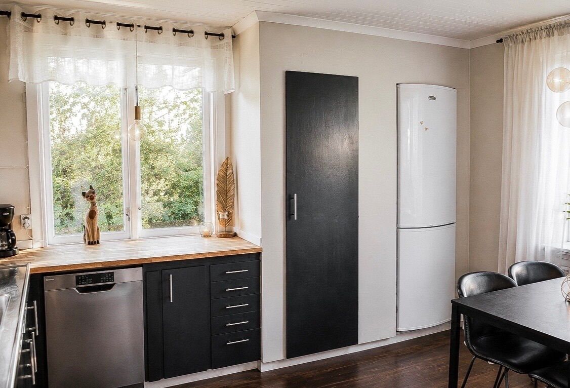 Una cocina moderna con lavavajillas, armarios negros y refrigerador.